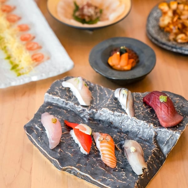 A variety of Yume Sushi Bar's sushi and sashimi are artfully arranged on a dark, textured plate.