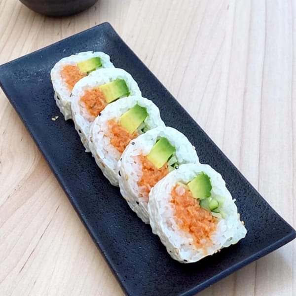 Five Yume Sushi Bar spicy tuna and avocado sushi rolls on a black rectangular plate.