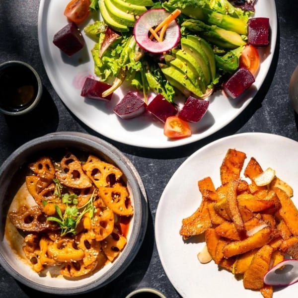 A vibrant Yume Sushi Bar meal with a fresh salad, lotus root, and sweet potato fries.