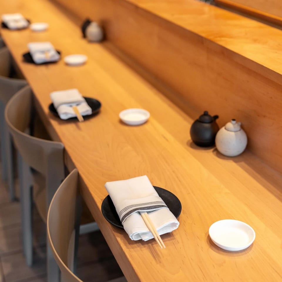 Sushi bar counter at Yume Sushi Bar with place settings, chopsticks, and small sauce dishes.