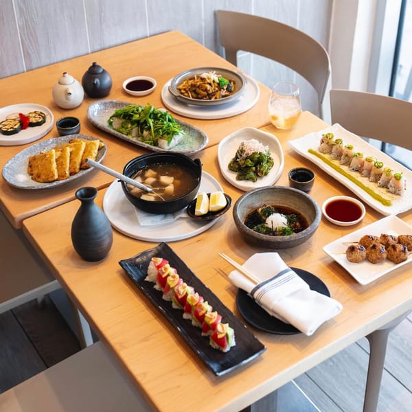 A wooden table laden with various sushi dishes, including rolls, soup, and small plates at Yume Sushi Bar.