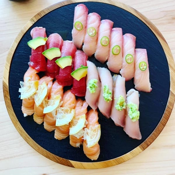 Assorted Yume Sushi Bar nigiri with tuna, salmon, and white fish, garnished with avocado, lemon, and wasabi.