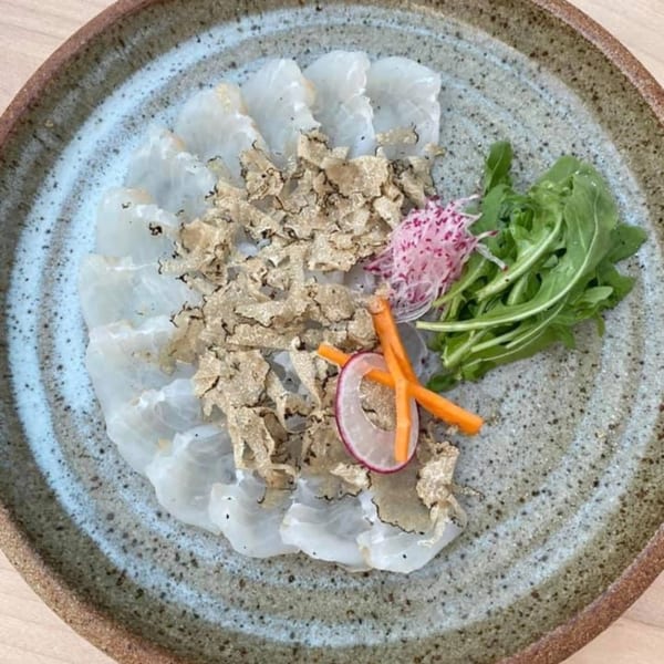 Yume Sushi Bar's delicate white fish sashimi with truffle shavings, arugula, and pickled vegetables.